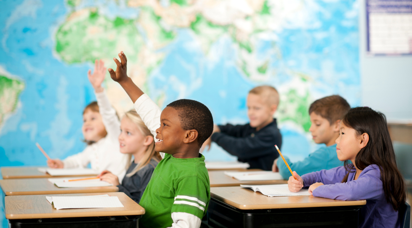 child in classroom raising hand